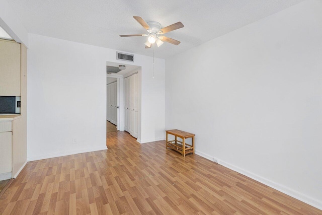 spare room with a textured ceiling, ceiling fan, and light hardwood / wood-style flooring