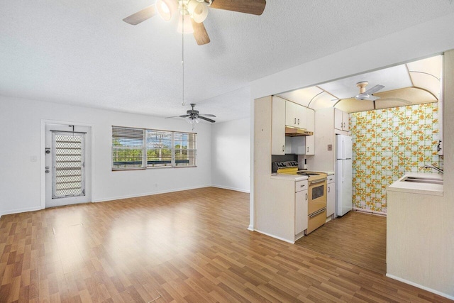 kitchen with light hardwood / wood-style floors, white appliances, sink, white cabinets, and a textured ceiling