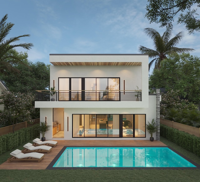 rear view of property featuring a fenced in pool, a balcony, and a lawn