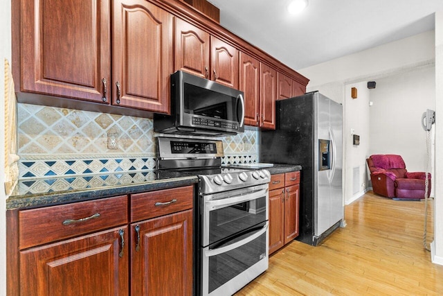 kitchen featuring light hardwood / wood-style floors, stainless steel appliances, dark stone counters, and tasteful backsplash