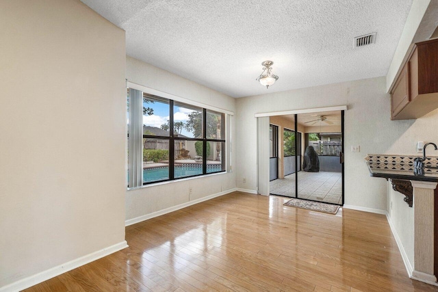 unfurnished dining area featuring light hardwood / wood-style floors and a textured ceiling