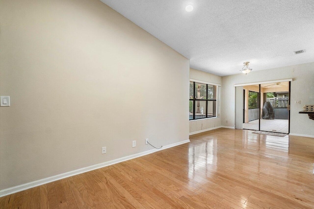 spare room with light hardwood / wood-style floors and a textured ceiling