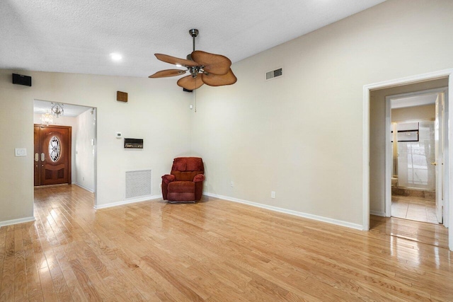 unfurnished living room featuring ceiling fan, lofted ceiling, a textured ceiling, and light hardwood / wood-style flooring