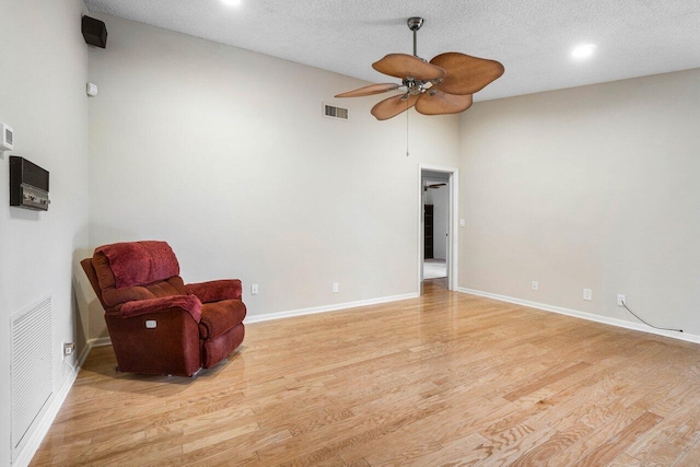 unfurnished room featuring baseboards, light wood-style flooring, visible vents, and a textured ceiling