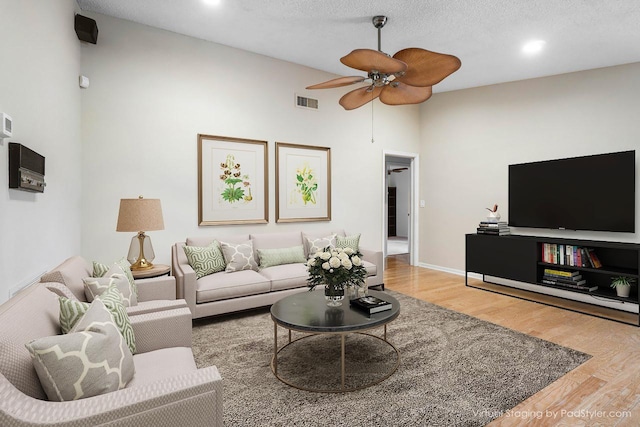 living area featuring ceiling fan, a textured ceiling, wood finished floors, and visible vents