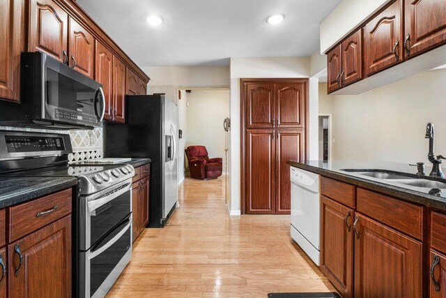 kitchen with recessed lighting, stainless steel appliances, a sink, light wood finished floors, and tasteful backsplash