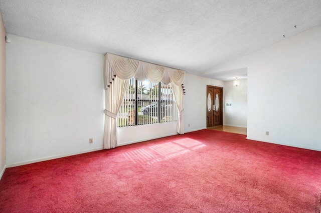 carpeted spare room with a textured ceiling and vaulted ceiling