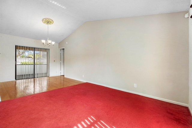 carpeted spare room with an inviting chandelier, baseboards, and vaulted ceiling