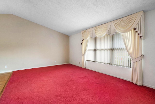 spare room featuring vaulted ceiling, a textured ceiling, carpet, and baseboards