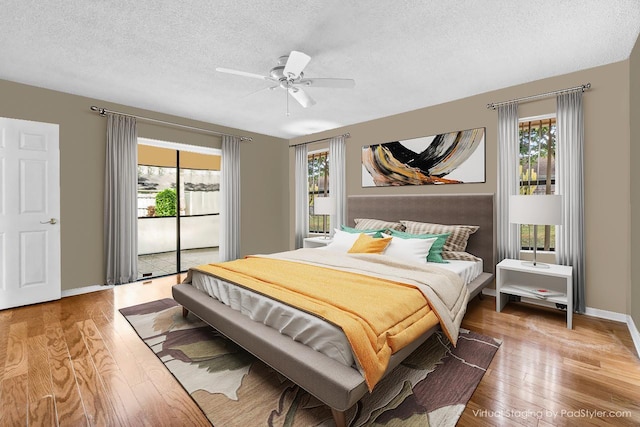 bedroom featuring access to exterior, multiple windows, a textured ceiling, and wood finished floors