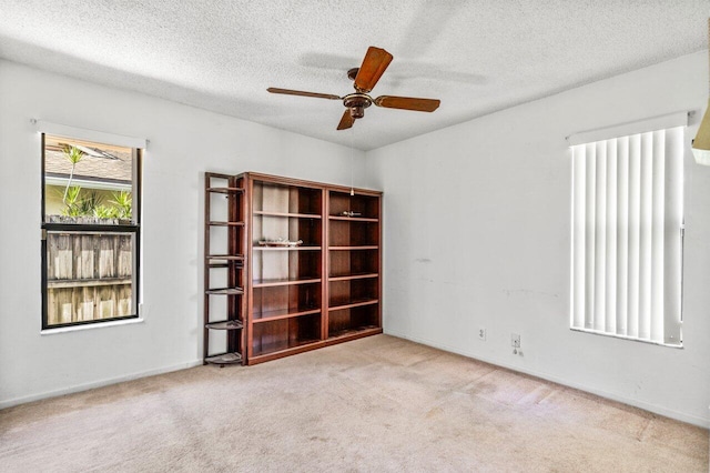 unfurnished room with a ceiling fan, light colored carpet, and a textured ceiling