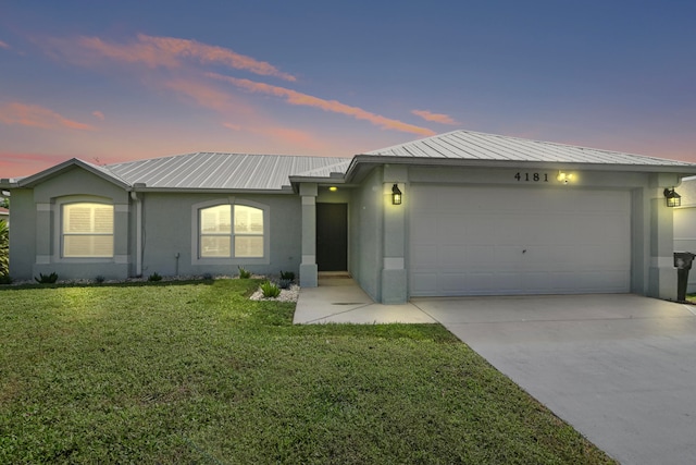 ranch-style home with a garage and a lawn