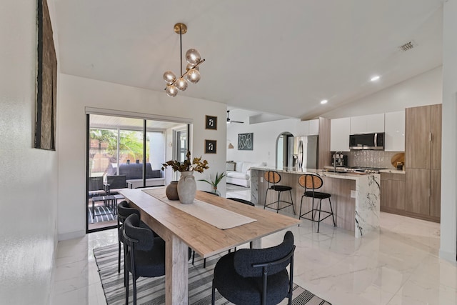 dining space with lofted ceiling and ceiling fan with notable chandelier