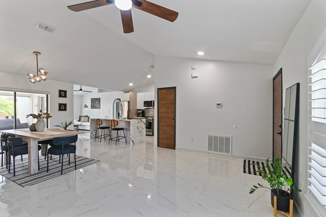 dining area with high vaulted ceiling and ceiling fan with notable chandelier