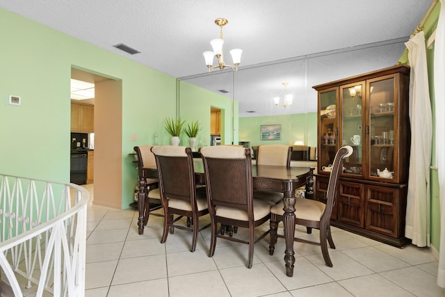 dining space featuring a notable chandelier, light tile patterned flooring, and a textured ceiling