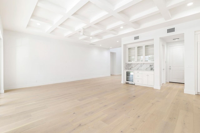 unfurnished living room featuring beverage cooler, baseboards, beamed ceiling, visible vents, and coffered ceiling