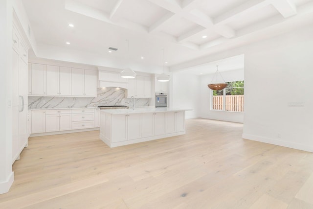 kitchen with light wood-type flooring, hanging light fixtures, white cabinets, decorative backsplash, and a center island with sink