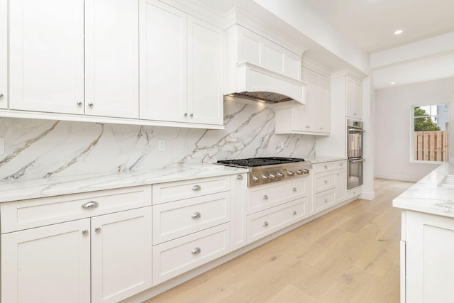 kitchen with white cabinetry, stainless steel appliances, light wood-type flooring, and tasteful backsplash