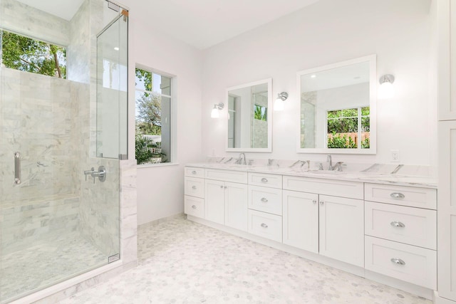 full bath featuring double vanity, a sink, baseboards, and a stall shower