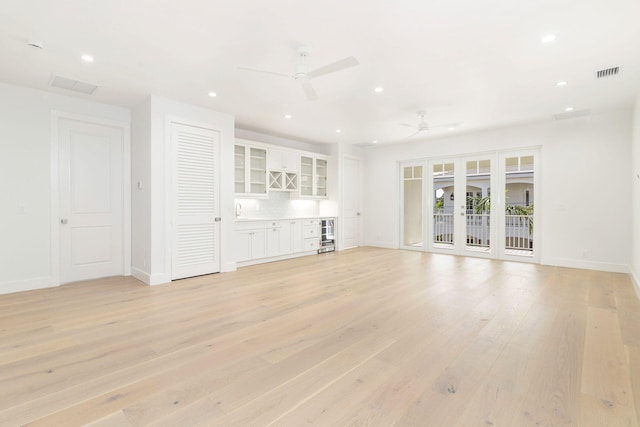 unfurnished living room with french doors, ceiling fan, and light hardwood / wood-style flooring