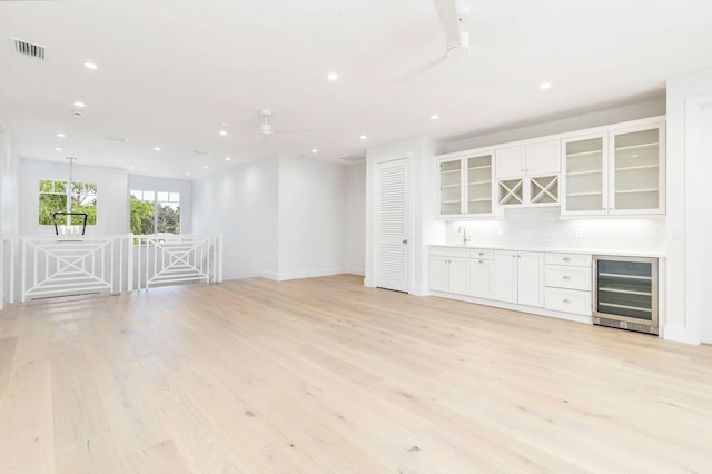 interior space with a ceiling fan, a sink, a bar, wine cooler, and recessed lighting