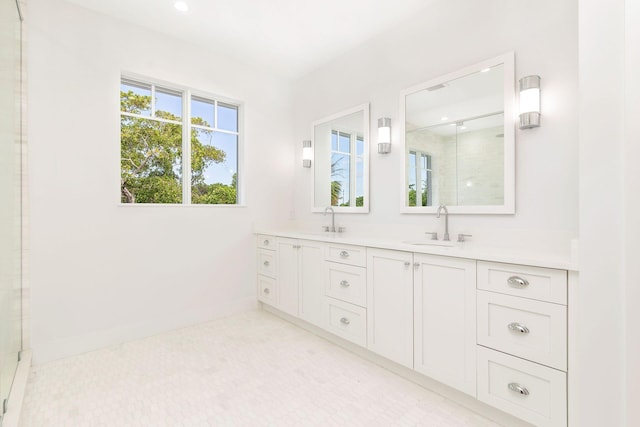 full bath with double vanity, baseboards, a sink, and a stall shower