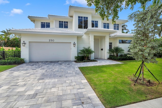 view of front of home featuring stucco siding, decorative driveway, fence, and a front yard