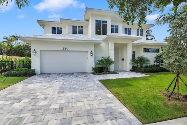 view of front of home featuring fence, a tile roof, stucco siding, a front yard, and decorative driveway