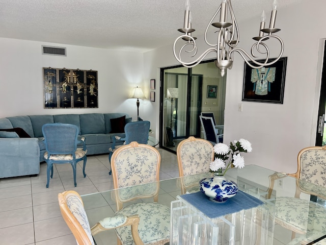 dining space with a textured ceiling, tile patterned flooring, visible vents, and an inviting chandelier