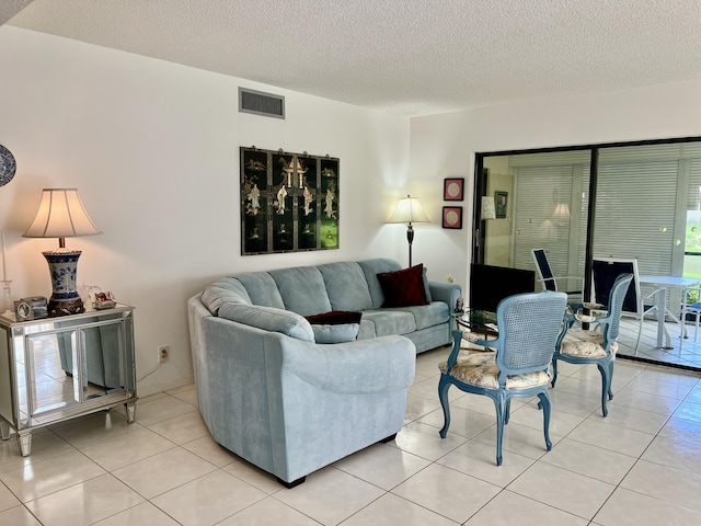 living room with visible vents, a textured ceiling, and light tile patterned floors