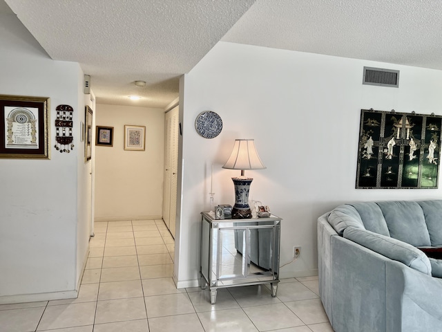 corridor featuring light tile patterned floors and a textured ceiling