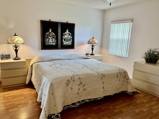 bedroom with a textured ceiling and wood finished floors