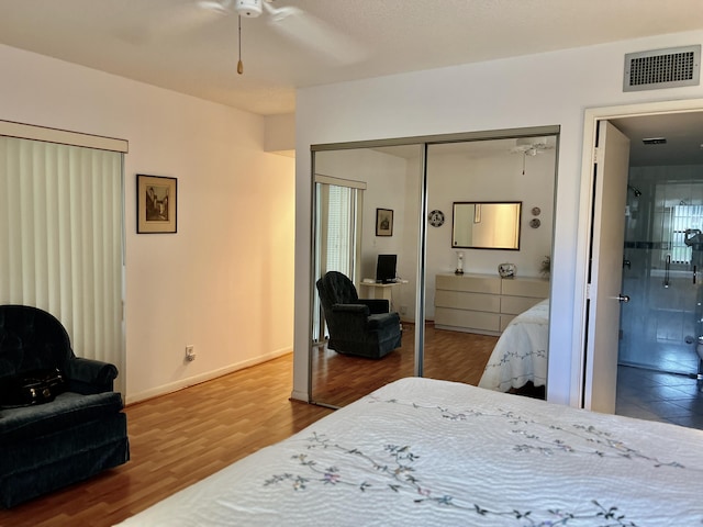 bedroom featuring connected bathroom, wood finished floors, visible vents, baseboards, and a closet