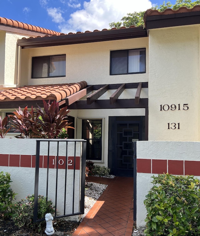 property entrance with a tile roof and stucco siding