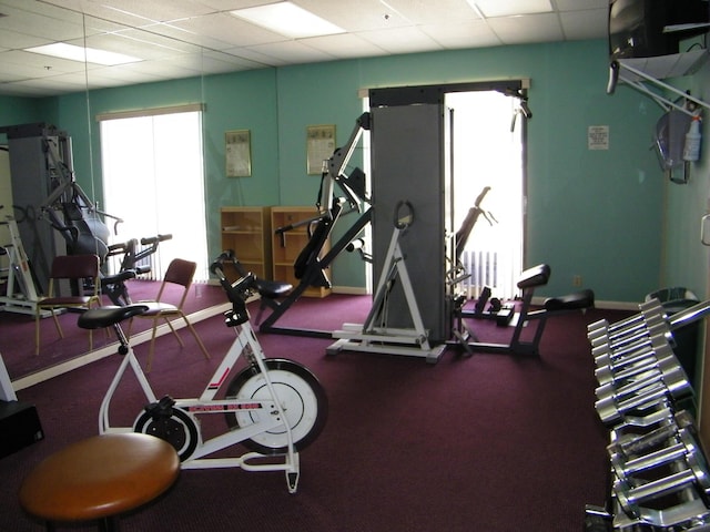 workout area featuring a drop ceiling and baseboards