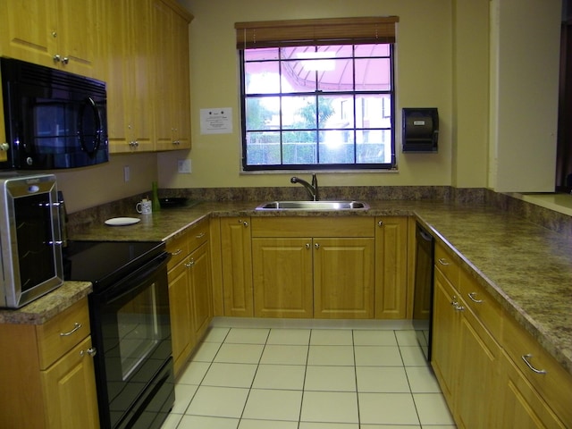 kitchen featuring light tile patterned floors, dark countertops, brown cabinets, black appliances, and a sink