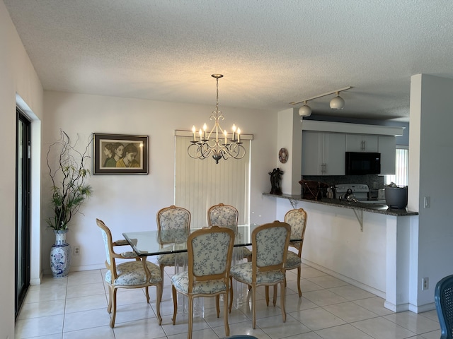 10915 Palm Lake Ave Unit 102, Boynton Beach, FL 33437 - dining space with a textured ceiling, baseboards, light tile patterned floors, and a chandelier