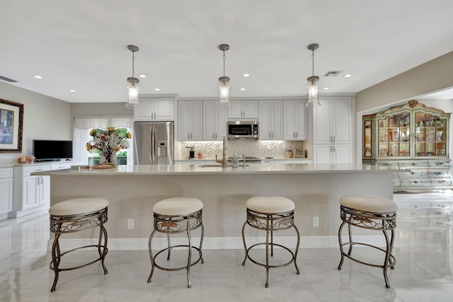 kitchen featuring a breakfast bar area, a large island, appliances with stainless steel finishes, and decorative light fixtures