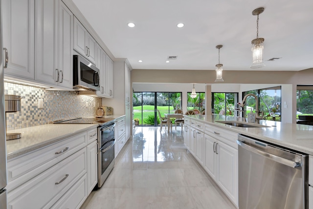 kitchen with hanging light fixtures, white cabinetry, light stone countertops, sink, and stainless steel appliances