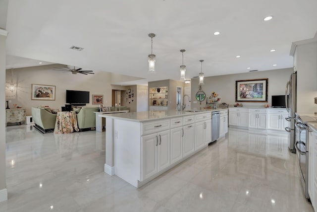 kitchen featuring appliances with stainless steel finishes, sink, a kitchen island, decorative light fixtures, and white cabinets