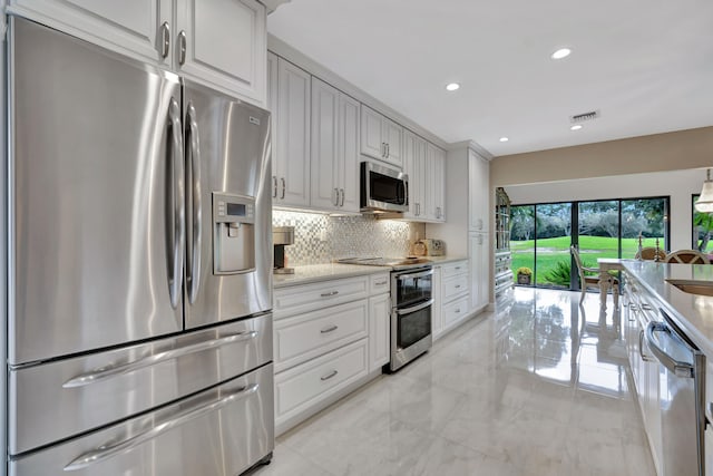 kitchen with white cabinetry, light stone counters, stainless steel appliances, and decorative backsplash