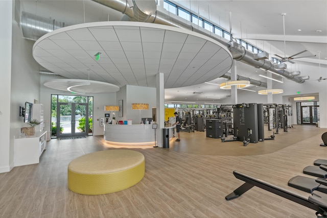 exercise room with french doors, a towering ceiling, and light wood-type flooring