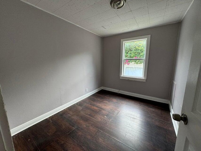 spare room with baseboards and dark wood-style floors