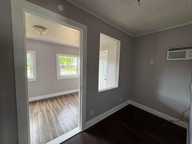spare room with baseboards, dark wood finished floors, a wall mounted air conditioner, and crown molding