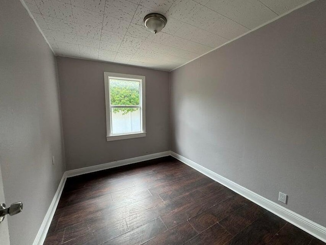 unfurnished room featuring baseboards and dark wood-style flooring