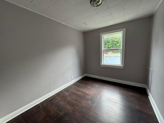 empty room featuring baseboards and dark wood-style floors