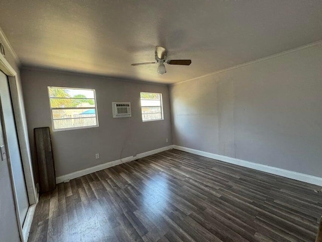spare room with an AC wall unit, crown molding, ceiling fan, baseboards, and dark wood-style floors