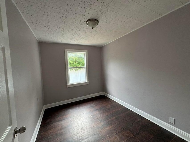 empty room featuring baseboards and dark wood-style flooring
