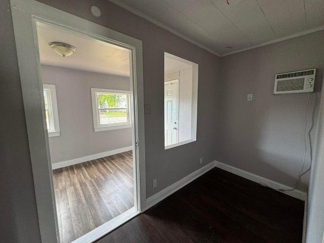 spare room featuring baseboards, an AC wall unit, ornamental molding, and dark wood-style flooring