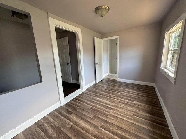 unfurnished bedroom featuring baseboards and dark wood-type flooring